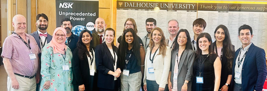 participants from Schulich Dentistry at COHS 2024 posing in front of a plaque at Dalhousie University