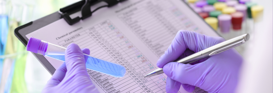 purple gloved hands holding test tube and clipboard